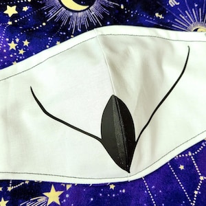 May include: White face mask with a black stylized design resembling a bird's beak.