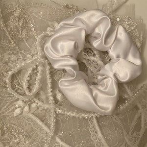 May include: A white satin scrunchie with a delicate lace and pearl trim.