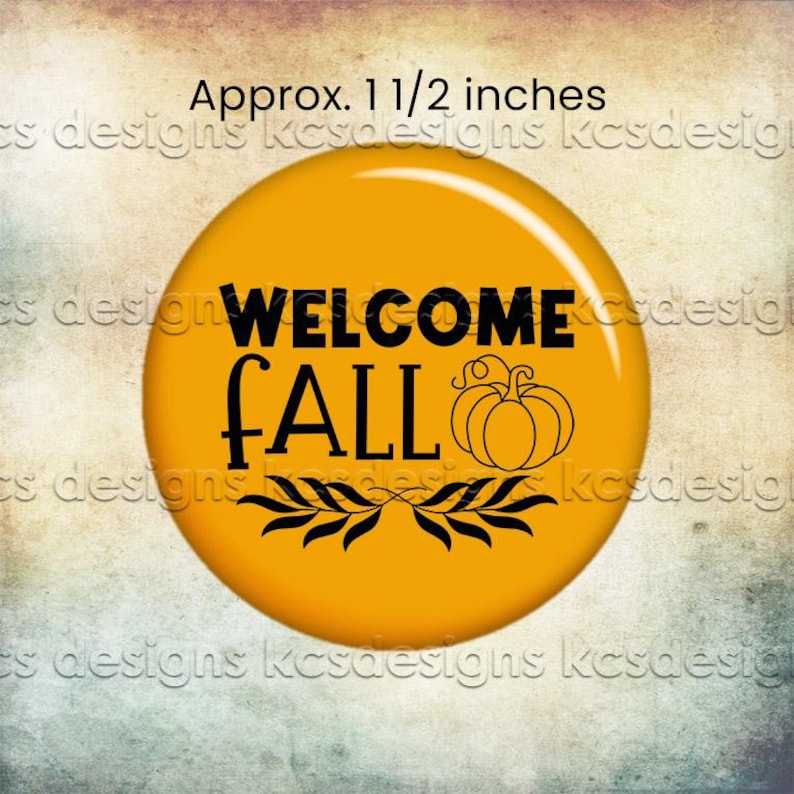 Może przedstawiać: Okrągły, pomarańczowy guzik z czarnym napisem "WELCOME FALL", ilustracją dyni i wzorem liści. Guzik ma średnicę około 3,8 cm.