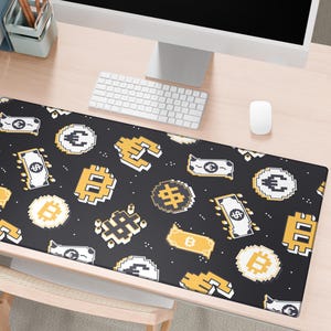 May include: Black rectangular desk mat with a repeating pattern of pixelated currency symbols, including dollar bills, Bitcoin, and Euro signs, in yellow and white. The mat is on a light wood desk with a keyboard and mouse.