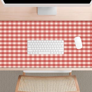 May include: A red and white checkered pattern desk mat with a white keyboard and mouse. The mat is rectangular and covers most of the desk surface. A small succulent plant and a pencil holder are visible on the desk.