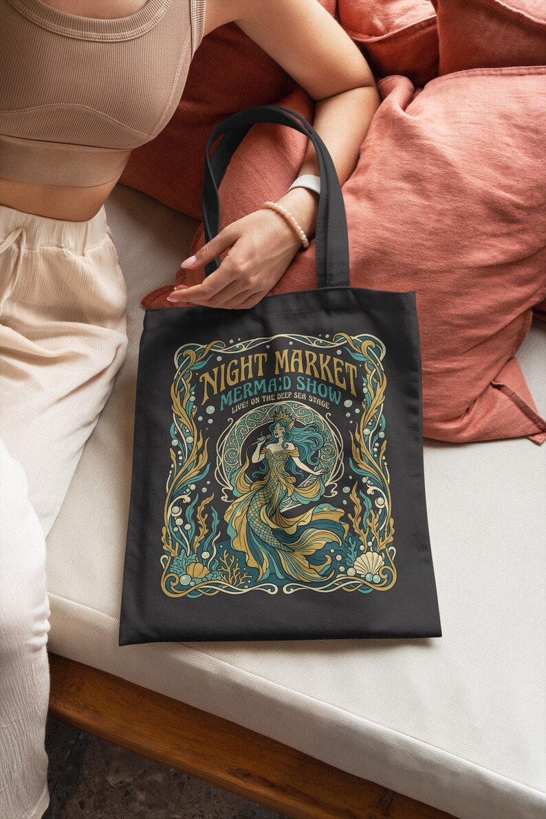 Black tote bag with "Night Market Mermaid Show" text and stylized mermaid artwork.