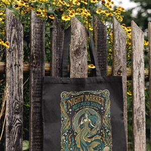 Black tote bag with "Night Market Mermaid Show" text and mermaid design.