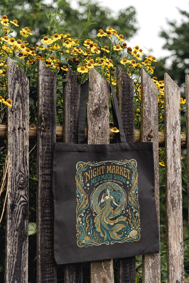 Black tote bag with "Night Market Mermaid Show" text and mermaid design.