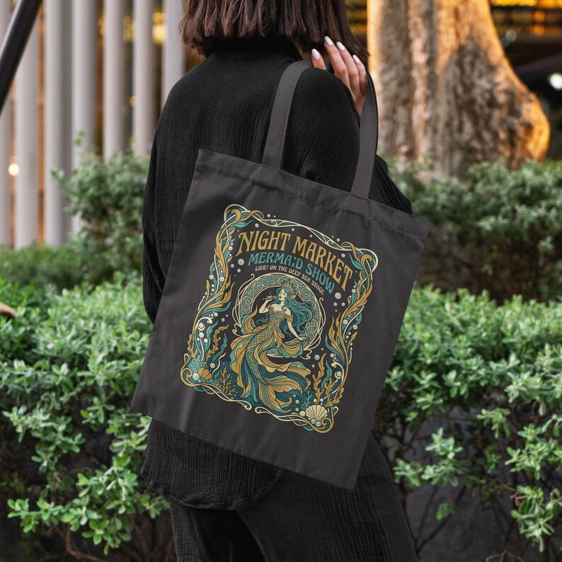 Black tote bag with "Night Market Mermaid Show" design featuring a mermaid and sea elements.