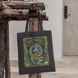 Black tote bag with a vintage mermaid illustration and "Night Market Mermaid Show" text.