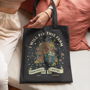 May include: Black tote bag featuring the text "I WILL FIX THIS FARM" and a farm scene graphic. The design includes banners with the words "Eventually" and "Maybe", and the dates "2024" and "Forever". The bag is held by a person.
