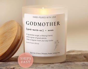 May include: A frosted glass candle with a bamboo lid and a white label featuring the text GODMOTHER, a definition, and a small flower illustration. The label includes the phrases Hand-poured with love, Burn time: 35 hours, and Phthalates, Paraben, Sulfates Free.