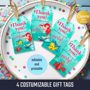 Peut inclure: Quatre &eacute;tiquettes cadeaux personnalisables avec un fond turquoise et un ruban dor&eacute;. Chaque &eacute;tiquette pr&eacute;sente le texte &laquo;&nbsp;Merci&nbsp;! Pour votre venue &agrave; ma f&ecirc;te&nbsp;!&nbsp;&raquo; et une illustration de sir&egrave;ne. Les &eacute;tiquettes sont dispos&eacute;es sur une assiette blanche avec des confettis color&eacute;s.