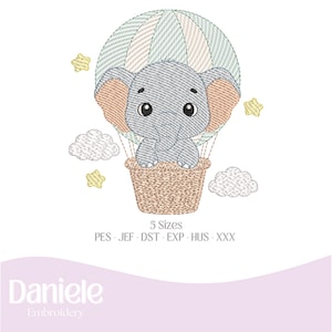 Pode incluir: Desenho bordado de um elefante bebé num balão de ar quente. O elefante é cinzento com orelhas cor de pêssego, sentado num cesto de vime. O balão é às riscas verdes e brancas, com nuvens e estrelas bordadas.