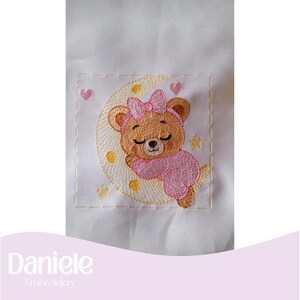 May include: Embroidered design of a sleeping teddy bear on a crescent moon, wearing a pink bow and outfit. The design includes yellow stars and pink hearts, all on a white background. The text "Daniele Embroidery" is at the bottom.