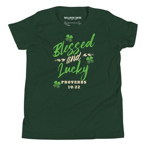 Puede incluir: Camiseta verde con el texto "Blessed and Lucky" en letras verdes y doradas. El texto "Proverbs 10:22" también está incluido en letras doradas.