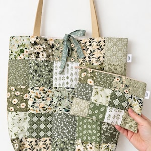 May include: A quilted tote bag and matching zippered pouch featuring a patchwork design of various green, white, and cream floral and botanical patterns. The tote has beige fabric handles and a fabric tie closure at the top centre.