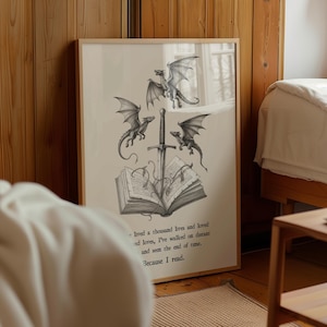 Könnte beinhalten: Ein gerahmter Druck mit einer Fantasy-Illustration. Das Kunstwerk zeigt drei Drachen, ein Schwert und ein offenes Buch. Der Text auf dem Druck lautet "Because I read." Der Druck befindet sich in einem Holzrahmen.