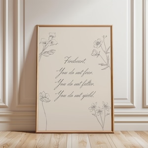 Könnte beinhalten: Ein gerahmter Druck mit beigem Hintergrund und floraler Strichzeichnung. Der Text lautet: „Fireheart, You do not fear. You do not falter. You do not yield.“ Der Rahmen ist hellbraun.