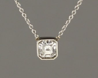 0.51 carat Asscher cut Diamond set in 18 kt white gold frame pendant with chain attached.