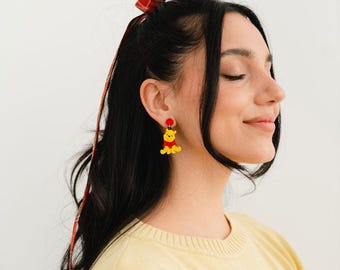 Ett par örhängen med Nalle Puh och Honung. Handgjorda i metakrylat med glänsande effekt och rostfritt stål.