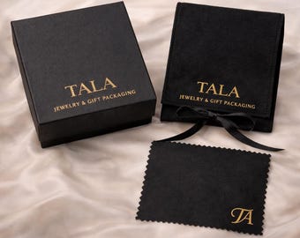 Puede incluir: Juego de embalaje de regalo de joyería negro con letras doradas. El juego incluye una caja, una bolsa con una cinta negra y un paño de limpieza. El texto "TALA JEWELRY & GIFT PACKAGING" está impreso en la caja y la bolsa.