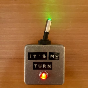 May include: A silver box with a red light and a green light. The box has the words "It's My Turn" on it.