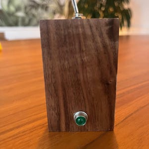 May include: A wooden toggle switch with a green LED light. The switch is mounted on a wooden block.
