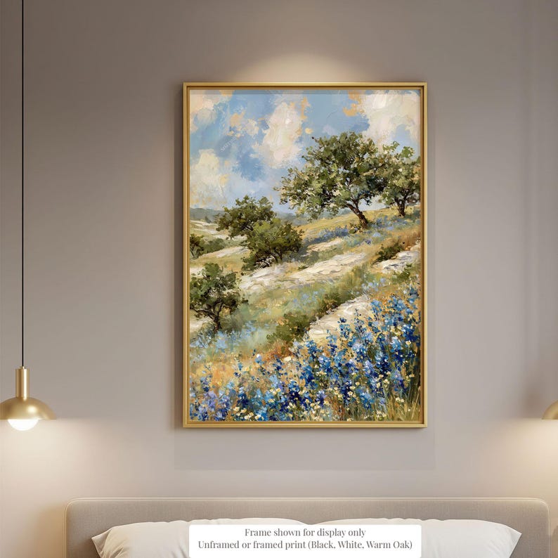 a framed painting of a scenic landscape with trees, flowers, and a blue sky with clouds.