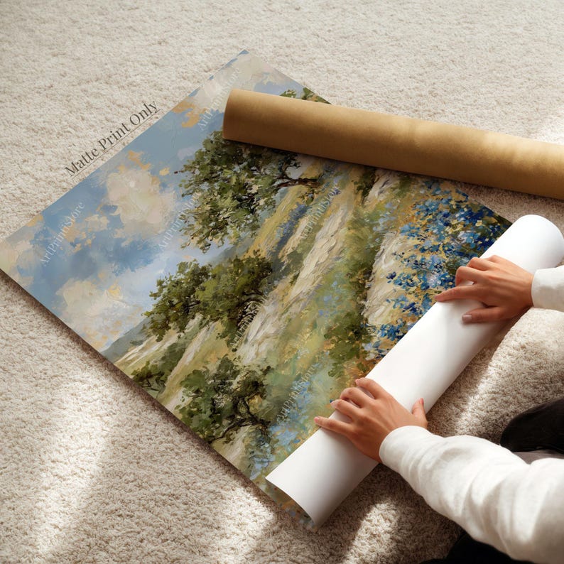 A person is carefully handling a roll of paper, likely preparing to print a landscape painting on a canvas.