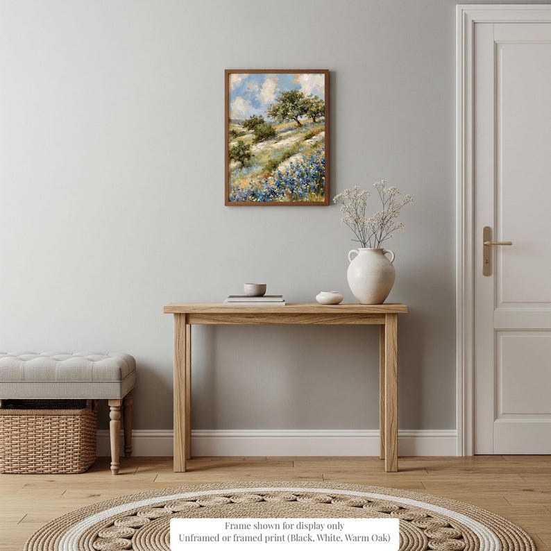 a serene and cozy living room with a wooden table, a white vase with flowers, and a framed painting of a field of flowers hanging on the wall.