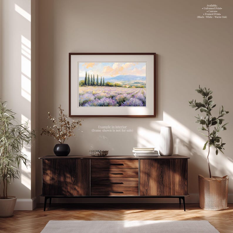 a wooden cabinet with a vase of flowers and a stack of books on top, set against a beige wall with a framed landscape painting hanging above it.