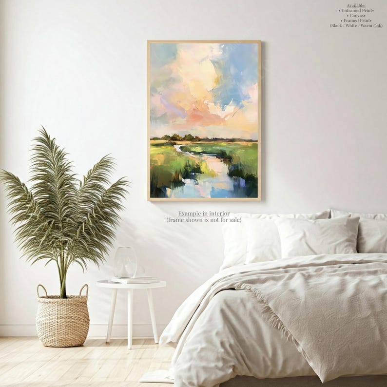 a serene bedroom scene with a large painting of a landscape hanging on the wall above a bed with white bedding. The room has a minimalist and modern design, with a potted plant and a small table adding a touch of greenery and functionality to the space.