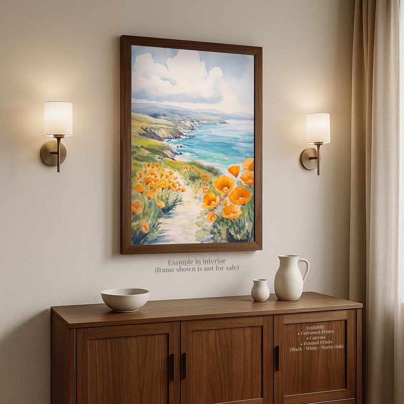 a painting of a coastal landscape with a path leading through a field of orange flowers, hanging on a wall above a wooden cabinet.