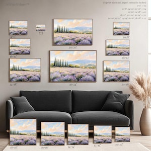 a collection of framed landscape paintings in various sizes, arranged on a wall next to a couch.