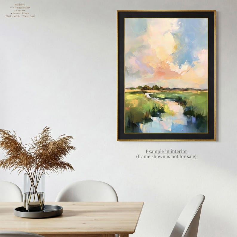 a painting of a landscape with a river and green fields, hanging on a wall above a wooden table with chairs.