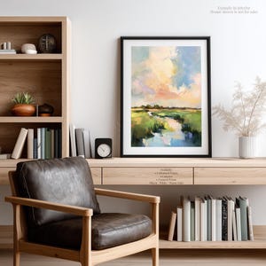 a cozy living room with a wooden bookshelf, a leather armchair, and a framed landscape painting on the wall.