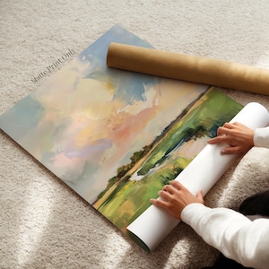 A person is carefully handling a large roll of paper, which appears to be a canvas print, and is unfolding it onto a carpeted floor.
