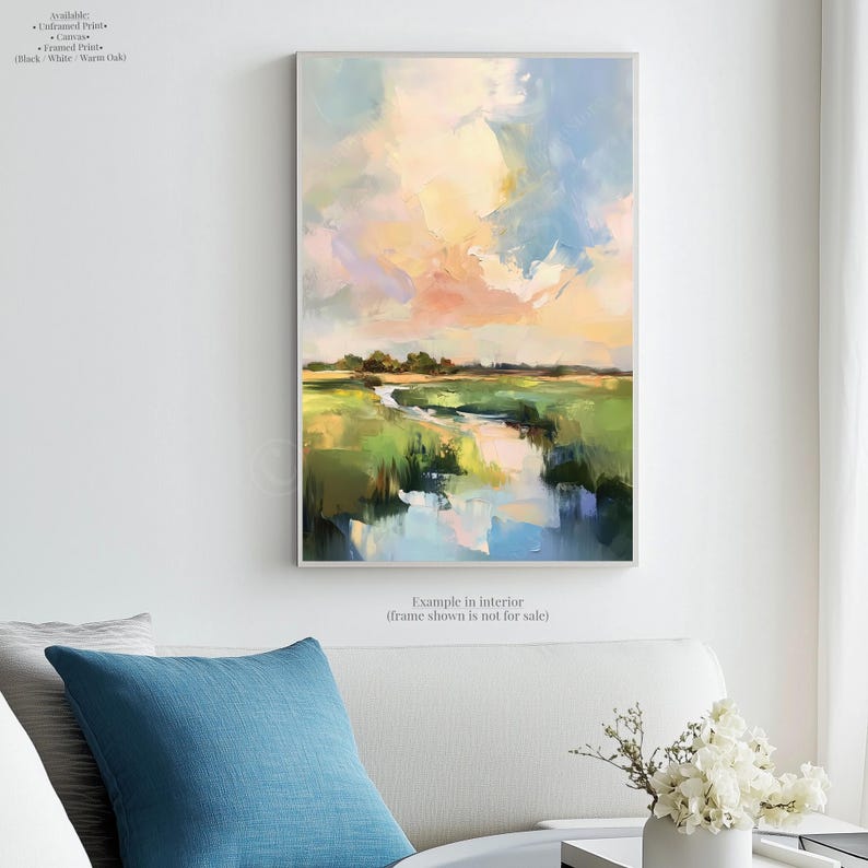 a large landscape painting hanging on a white wall, with a blue pillow on a couch in the foreground.
