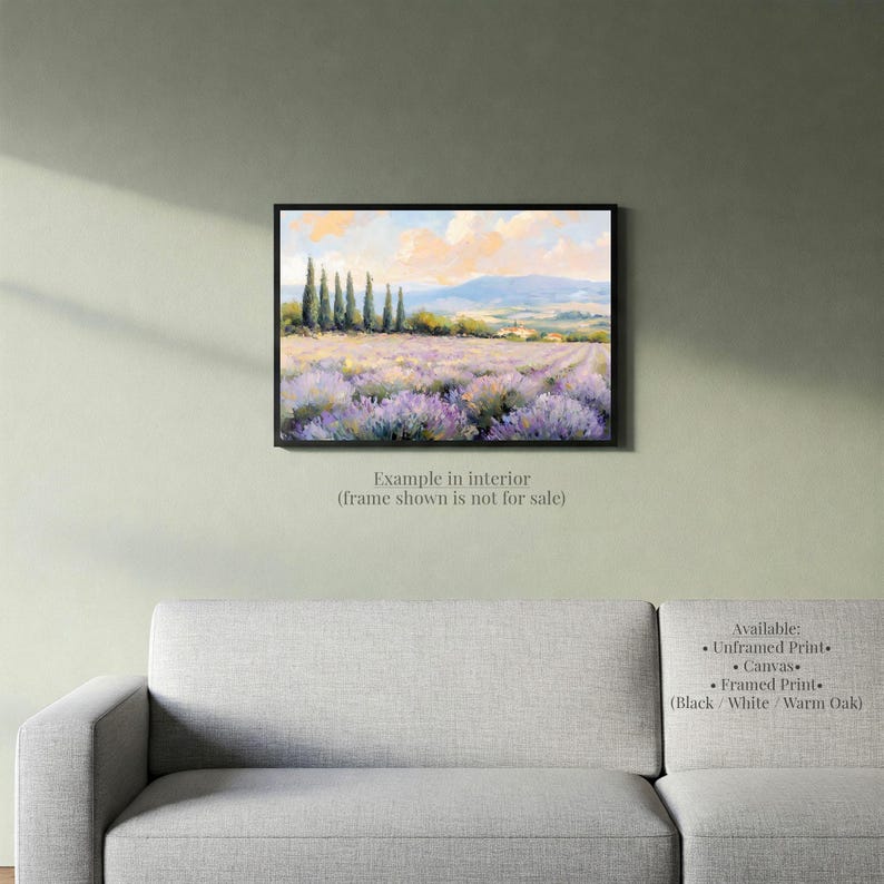 a painting of a field of lavender flowers hanging on a wall above a gray couch.