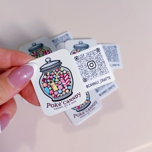 May include: Square stickers featuring a jar of colorful candies with a Pikachu design. The text "Poké'Canndy Pokémon art & more" is below the jar. A QR code and Instagram handle are also included.
