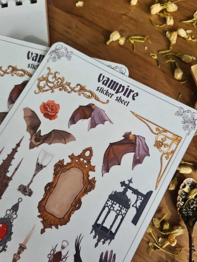 May include: A sheet of vampire-themed stickers featuring bats, a rose, a mirror, and other gothic elements. The stickers are on a white background with the words "vampire sticker sheet" printed on the top.