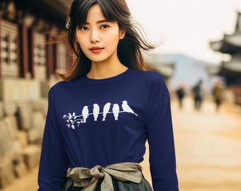 Könnte beinhalten: Ein marineblaues Langarmshirt mit einer weißen Grafik von fünf Vögeln auf einem Ast. Die Vögel sind horizontal über der Brust angeordnet. Das Shirt besteht aus einem weichen Material.