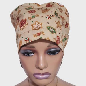 May include: A beige scrub cap featuring a pattern of gingerbread biscuits, candy canes, and Christmas tree motifs. The cap is made from a soft material and is designed for a comfortable fit. This festive cap is suitable for healthcare professionals or anyone seeking a holiday-themed accessory.