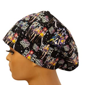 May include: Black cap with a repeating pattern of anime-style figures in colourful outfits. The cap also has the text "K-Pop Demon Hunters" and "Huntrax" in white. The cap is worn on a mannequin head.