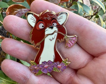 May include: A red fox with a white chest and a flower in its mouth. The fox is surrounded by purple flowers with gold accents. The pin is a cartoon character.