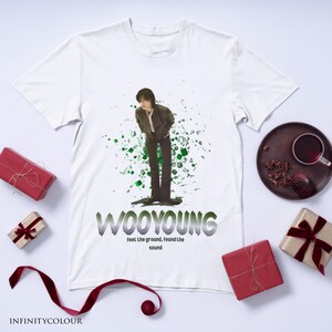 Puede incluir: Camiseta blanca con un gr&aacute;fico verde y negro de una persona de pie frente a un fondo verde y negro. El texto "WOOYOUNG" est&aacute; impreso en letras negras y grises debajo del gr&aacute;fico. El texto "feel the ground, found the sound" est&aacute; impreso en letras negras debajo del texto "WOOYOUNG".