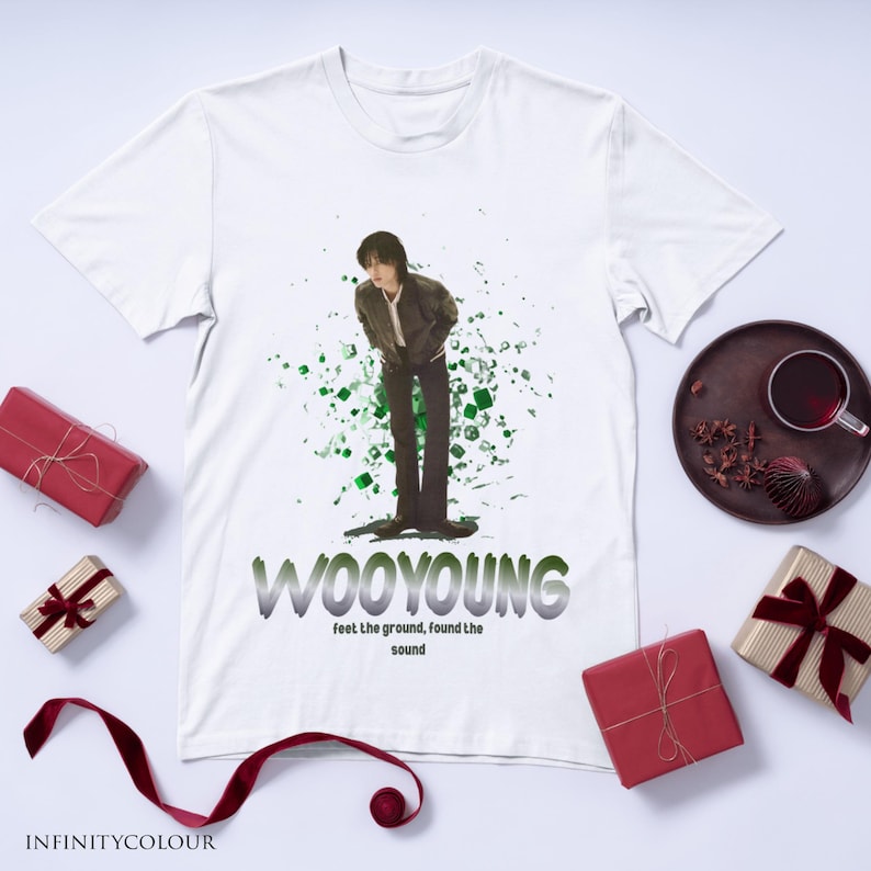 Puede incluir: Camiseta blanca con un gr&aacute;fico verde y negro de una persona de pie frente a un fondo verde y negro. El texto "WOOYOUNG" est&aacute; impreso en letras negras y grises debajo del gr&aacute;fico. El texto "feel the ground, found the sound" est&aacute; impreso en letras negras debajo del texto "WOOYOUNG".