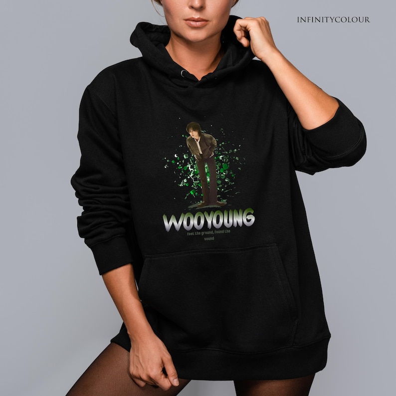 Puede incluir: Sudadera con capucha negra con un estampado gr&aacute;fico verde y blanco de una persona de pie frente a un dise&ntilde;o de salpicaduras verde y blanco. El texto "WOOYOUNG" est&aacute; impreso en una fuente plateada debajo del gr&aacute;fico. El texto "Feel like a god, walk, follow the sound" est&aacute; impreso en una fuente m&aacute;s peque&ntilde;a debajo del nombre.