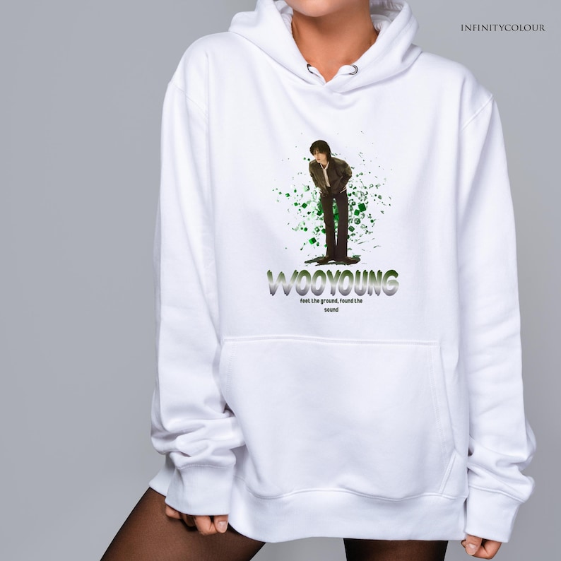 Puede incluir: Sudadera con capucha blanca con un gr&aacute;fico verde y blanco de una persona de pie con el texto "WOOYOUNG Feel the ground, found the sound" impreso en la parte delantera.