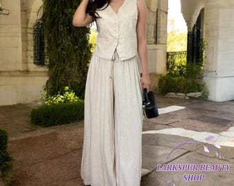 May include: A beige linen vest and wide-leg pants set. The vest has a V-neck and button closure. The pants have a drawstring waist. The outfit is made of a lightweight fabric, perfect for warm weather. The outfit is from Larkspur Beauty Shop.