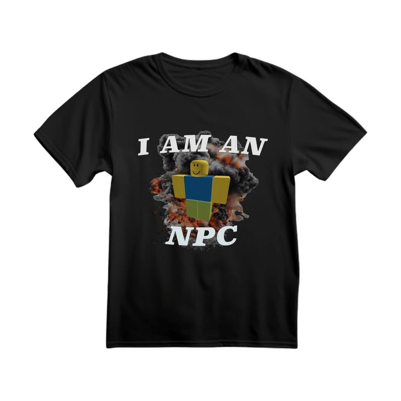 Peut inclure: T-shirt noir avec l'inscription blanche "I AM AN NPC" au-dessus d'un personnage de dessin anim&eacute; avec une t&ecirc;te jaune, un torse bleu et des jambes vertes. Le personnage est plac&eacute; sur un fond de fum&eacute;e orange et grise.