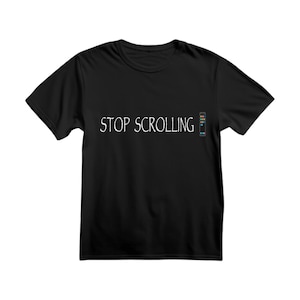 May include: Black t-shirt with the white text "STOP SCROLLING". A small graphic with the words "MORE TIME TO READ" is on the right side of the shirt. The shirt is made of a soft material.