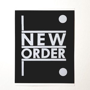 May include: Black and white sticker with the text "NEW ORDER" in a bold, sans-serif font. The sticker has two white circles on either side of the text.